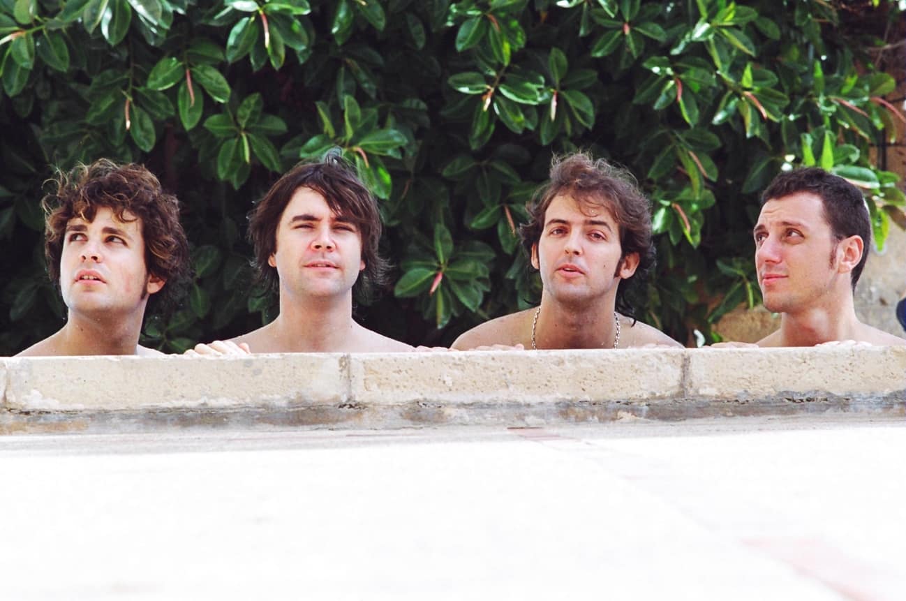 Miembros de la banda apoyados en una pared